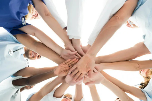 Circle of clinicians and coaches joining hands, representing coordinated care