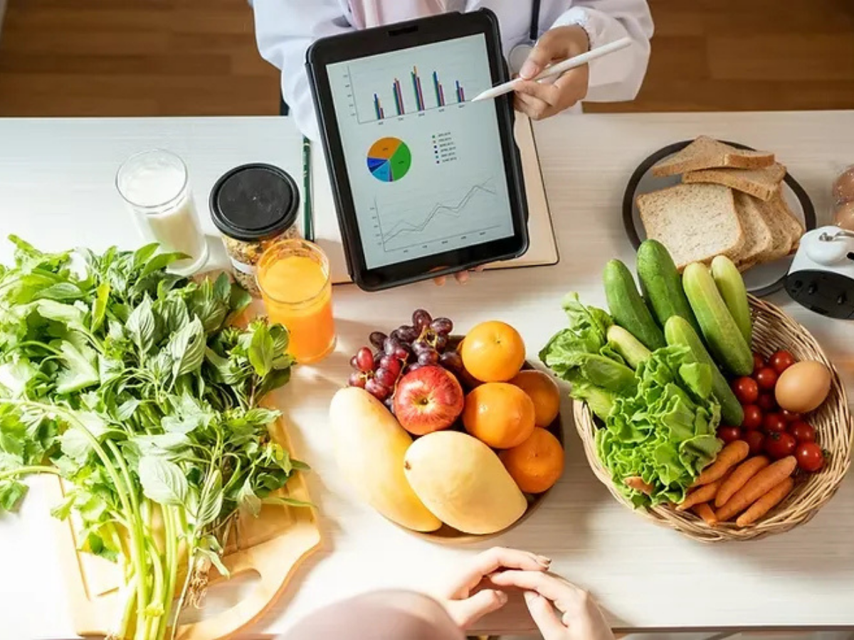 Doctor reviewing a patient's nutrition and lab data beside a table of fresh produce