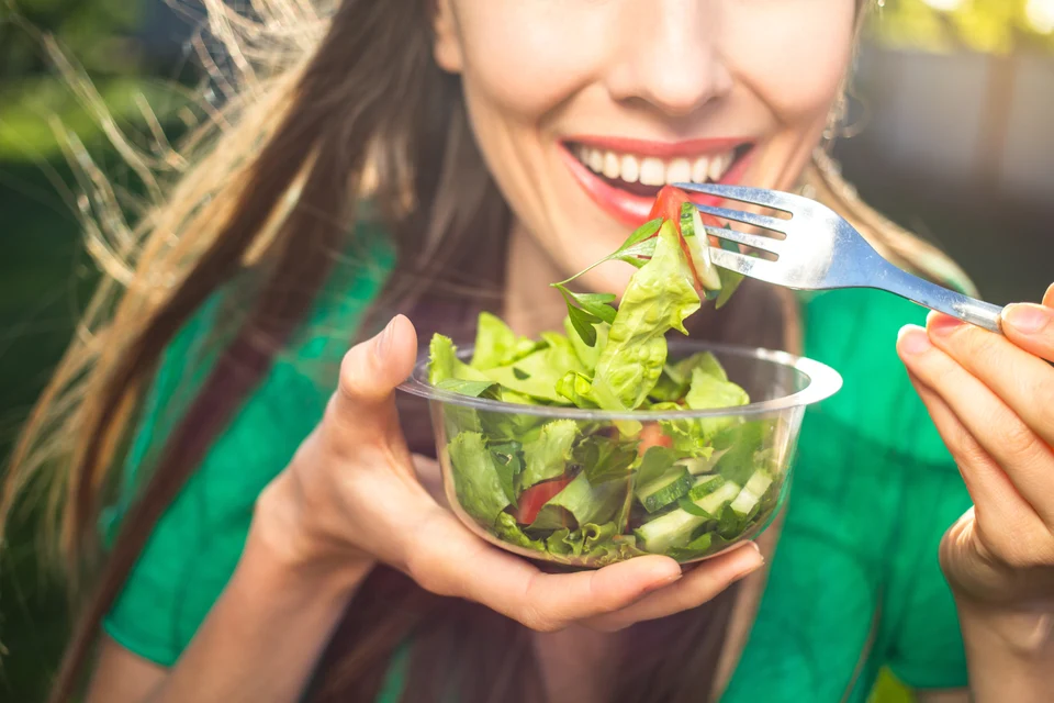 Woman eating a fresh salad outdoors